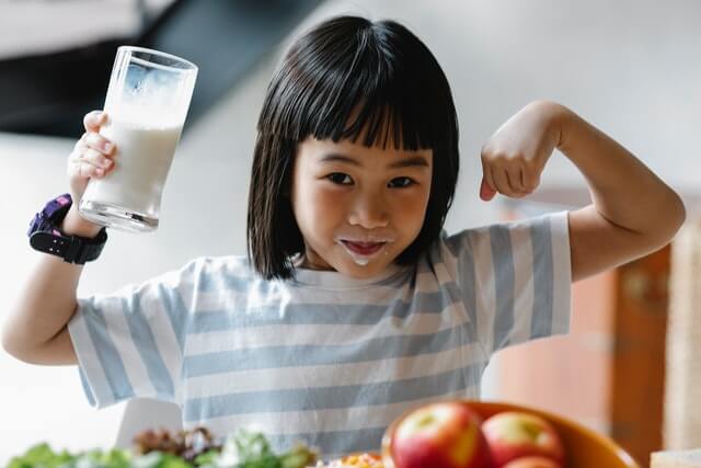 A girl looking at the camera while drinking milk.